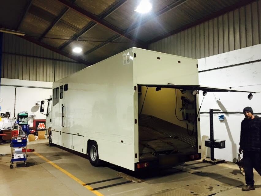 A large motorhome body inside the Lopham Vehicle Services workshop, with a mechanic beside it